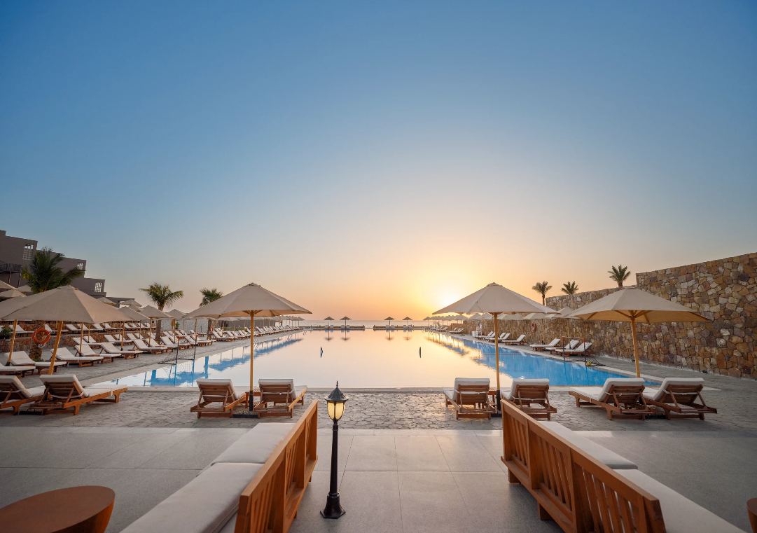 Infinity-Pool mit Liegen und Sonnenschirmen im Aldiana Club Naga Bay bei Sonnenuntergang